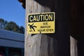 Sign alerting pedestrians to possible icy conditions, Ã¢â¬ÅCaution Ice Watch Your Step,Ã¢â¬Â fastened to a wooden post Royalty Free Stock Photo